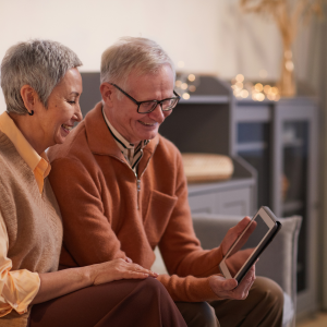 Elderly woman using a tablet while seated in a cozy, affordable modular home.